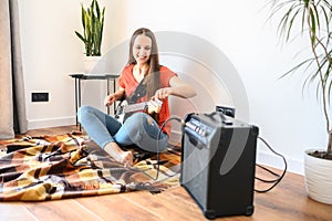 Young woman plays electric guitar at home