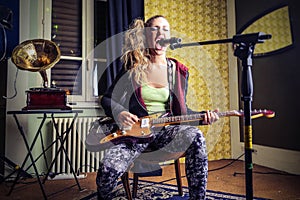 Young woman playing the eletric guitar and singing