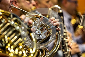 Young woman playing on french horn during philharmonic concert