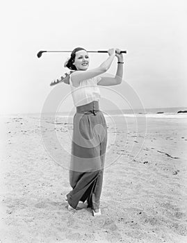 Young woman playing golf at the beach