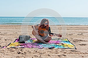 Young woman playing guitar on the beach