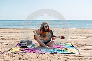 Young woman playing guitar on the beach