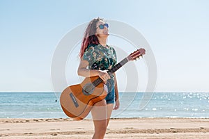 Young woman playing guitar on the beach
