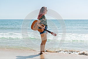 Young woman playing guitar on the beach