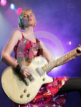 Young Woman playing guitar in concert on stage low angle view