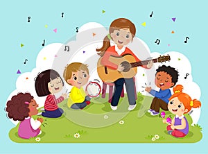 Young woman playing guitar with a group of kids singing and playing musical instruments. Female teacher and pupils having music in photo