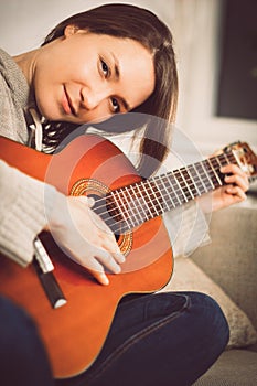 Young woman playing guitar at home. Relaxed happy young woman with music instrument portrait