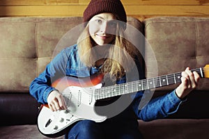 Young woman playing guitar. Home atmosphere on background.