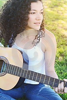 Young woman playing guitar at the park.