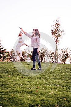 young woman playing with her dog at the park. autumn season. dog jumping