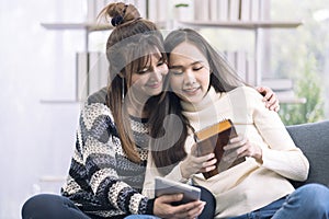 A young woman playing kalimba and using a tablet on the sofa in the living room