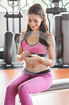 young woman playing mobilephone while take a break during workout