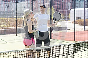 young woman playing Padel Tennis with partner in the open air tennis court