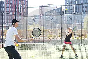 young woman playing Padel Tennis with partner in the open air tennis court