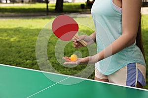 Young woman playing ping pong in park, closeup. Space for text