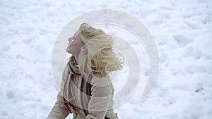 Young woman playing snow ball fight in winter. Girl in snowballs game. Female in knit handmade hat and mittens with