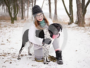 Young woman playing snow winter outdoors hugging cute adopted blind setter dog. Kindness and humanity concept.