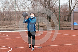 A young woman is playing sports on a sports field in a mask. Protection from coronavirus infection with a medical mask