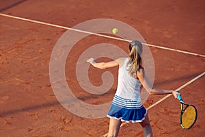 Young woman playing tennis on clay. Forehand.