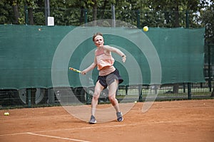 A young woman playing tennis hits forehand. Open ground.