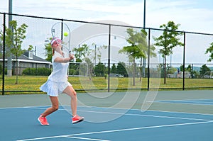 Young woman is playing tennis on the tennis court