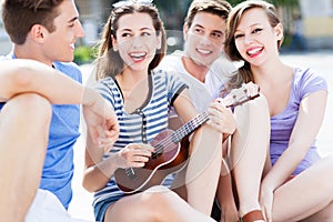 Young woman playing ukulele for friends