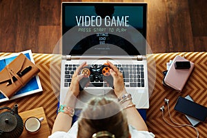 Young woman playing video games on laptop using joystick