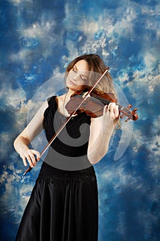 Young woman playing the violin against blue background