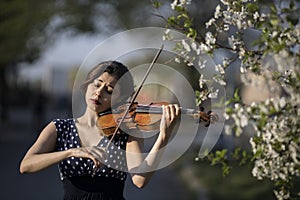 young woman playing violin outdoors