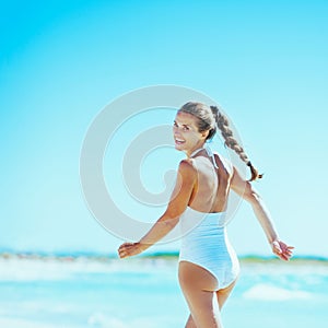 Young woman playing with waves on beach. rear view