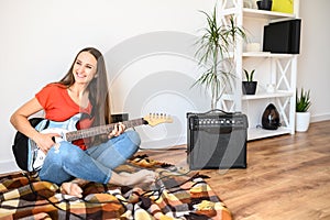 Young woman plays electric guitar at home