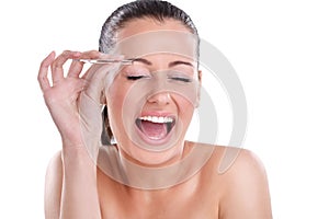 Young woman plucking her eyebrows with tweezers