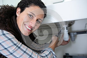 young woman plumber fitting waste on kitchen sink