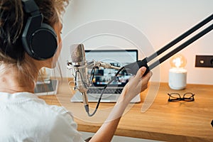 Young woman podcaster recording her voice into microphone