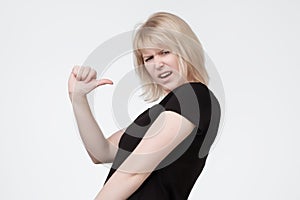 Young woman pointing on herself verbally defending herself, having perplexed and puzzled expression