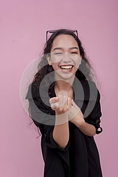 A young woman pointing and making fun of someone, mocking their appearance. Isolated on a light pink background