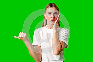 Young Woman Pointing at Something against green background