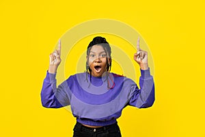 Young Woman Pointing Upwards on a Yellow Background