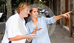 Young woman pointing way to middle aged female