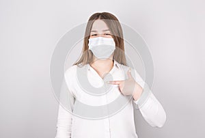 Young woman points her finger at herself. Shows the importance of wearing a mask for prevention of coronavirus infection and colds