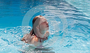 A young woman in the pool with her eyes closed, came up out of t