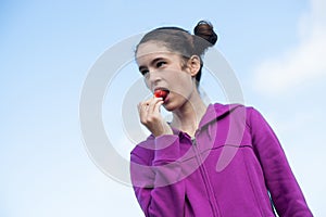 Young woman pops strawberry into mouth while picking
