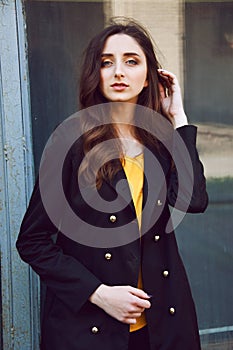 Young woman portrait in black trenchcoat and yellow blouse photo