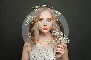 Young woman portrait. Cute female model with natural makeup and healthy curly hair holding flowers