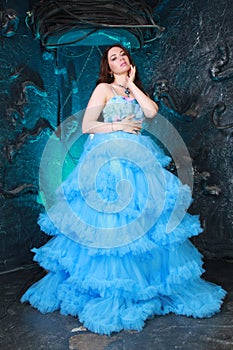 Young Woman Portrait in Evening Blue Long Dress on studio background