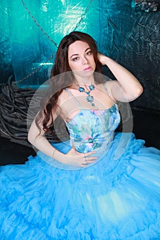 Young Woman Portrait in Evening Blue Long Dress on studio background