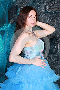 Young Woman Portrait in Evening Blue Long Dress on studio background