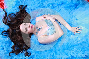 Young Woman Portrait in Evening Blue Long Dress on studio background