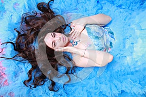 Young Woman Portrait in Evening Blue Long Dress on studio background