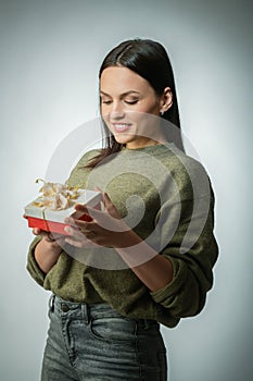 Young woman portrait hold gift in christmas color style . Smiling happy girl onn a light blue-green background